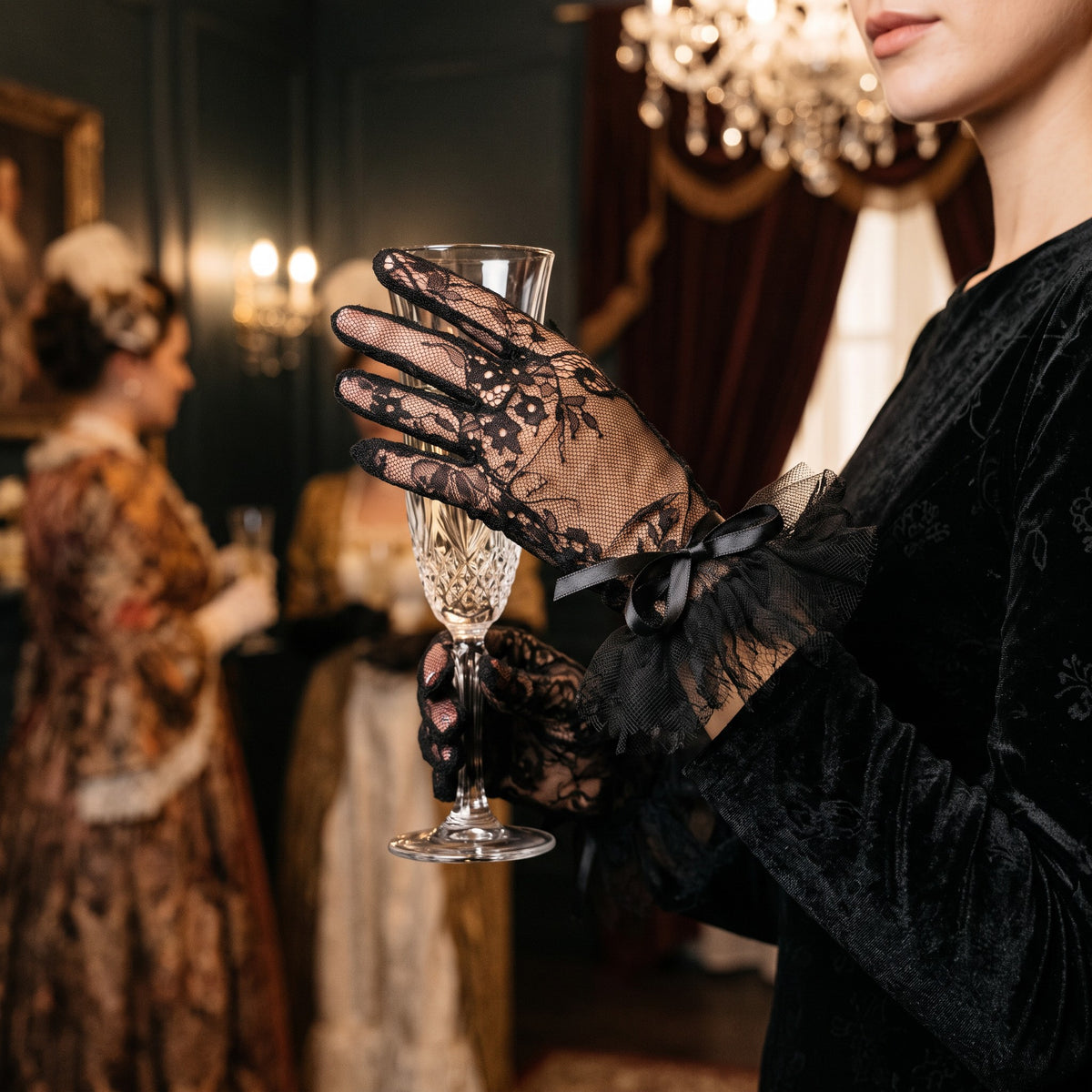 Black floral lace wrist gloves with a black tulle ruffle cuff and satin bow.