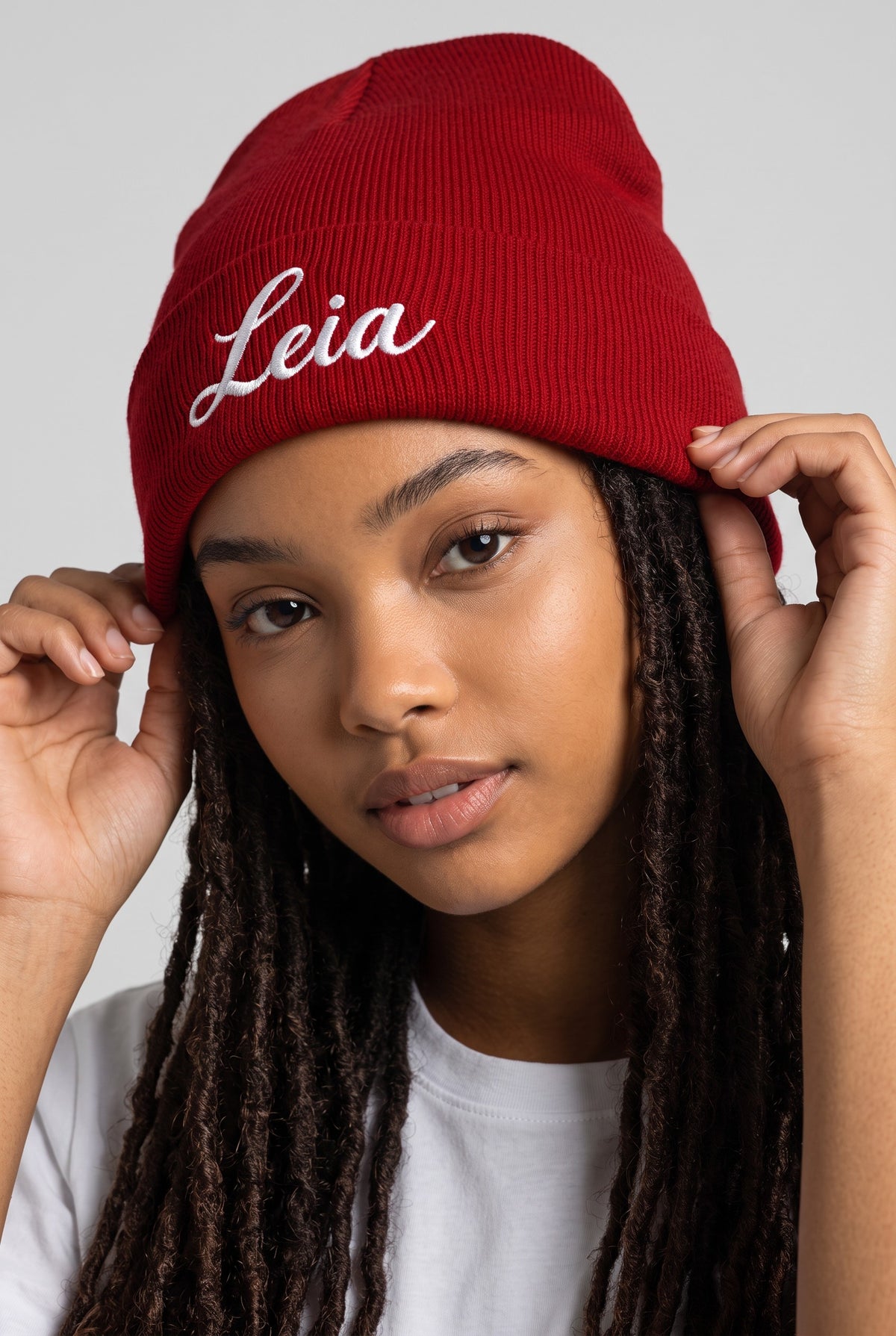 Model wearing a red Eddia beanie with custom cuff embroidery