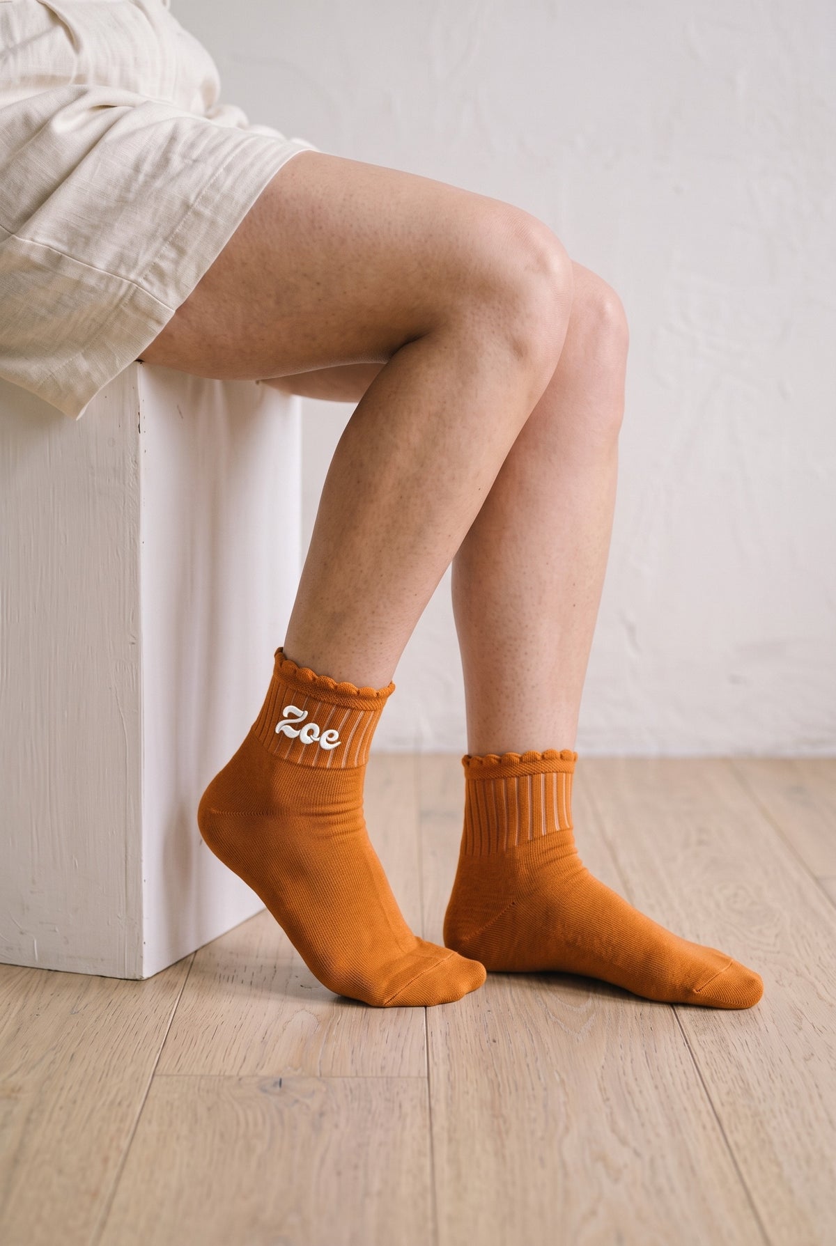 Model wearing orange embroidered ruffle ankle socks