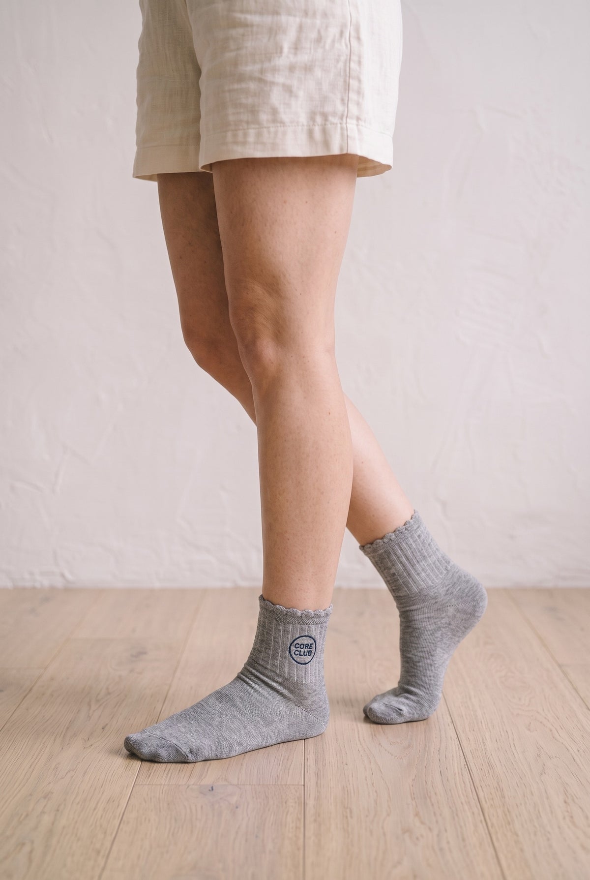 Model wearing light grey embroidered ruffle ankle socks, second view