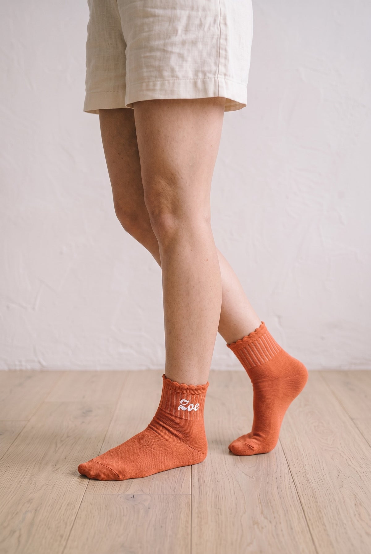 Model wearing orange embroidered ruffle ankle socks, second view