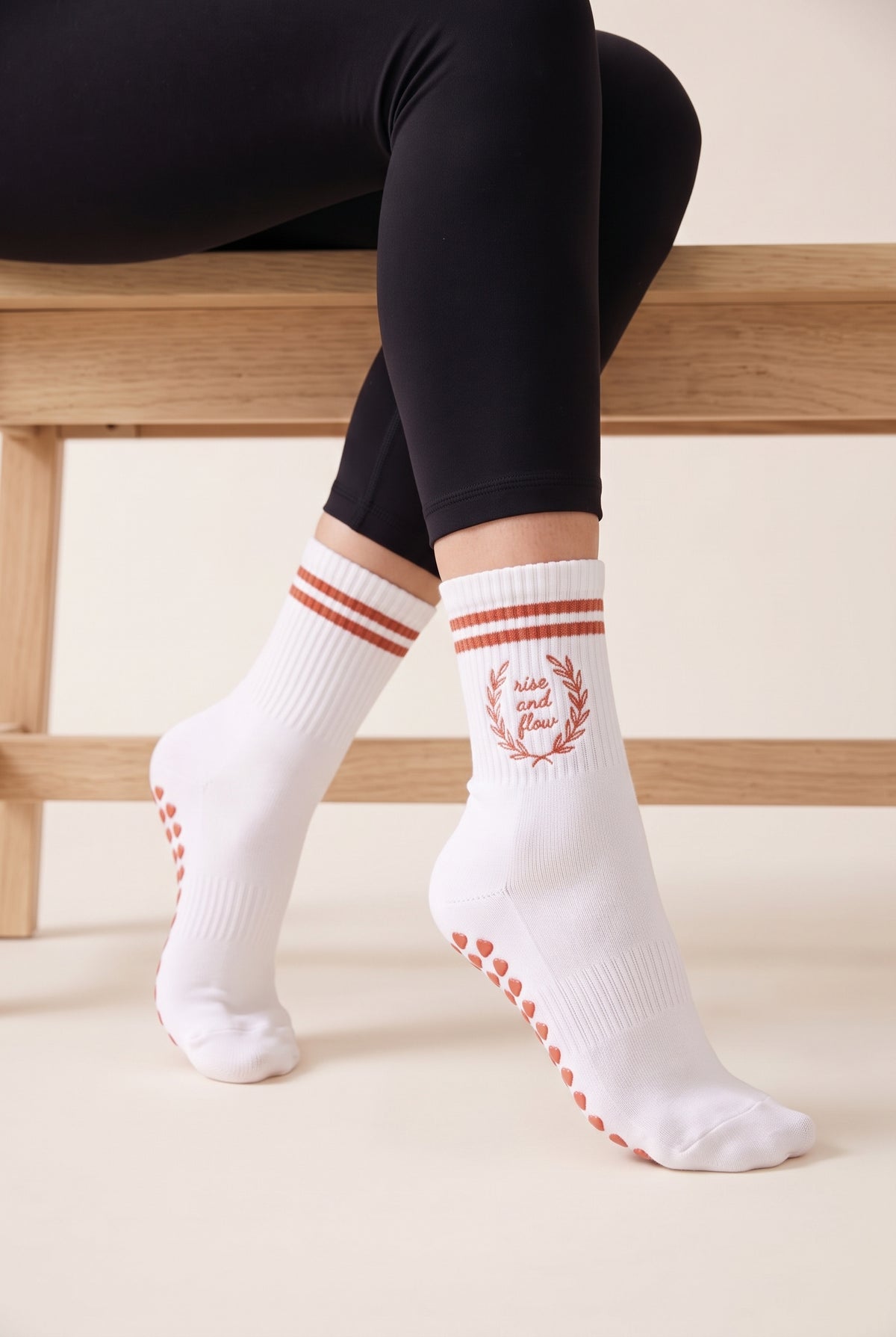 Model wearing coral crew pilates grip socks beside a studio bench