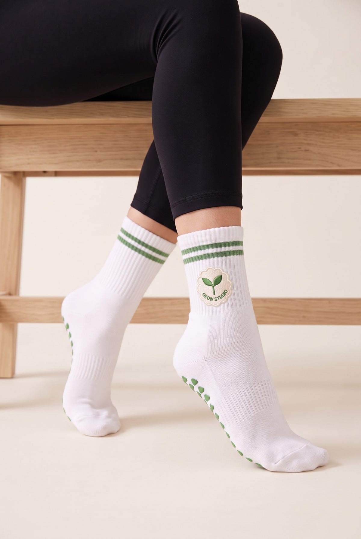 Model wearing green crew pilates grip socks beside a studio bench