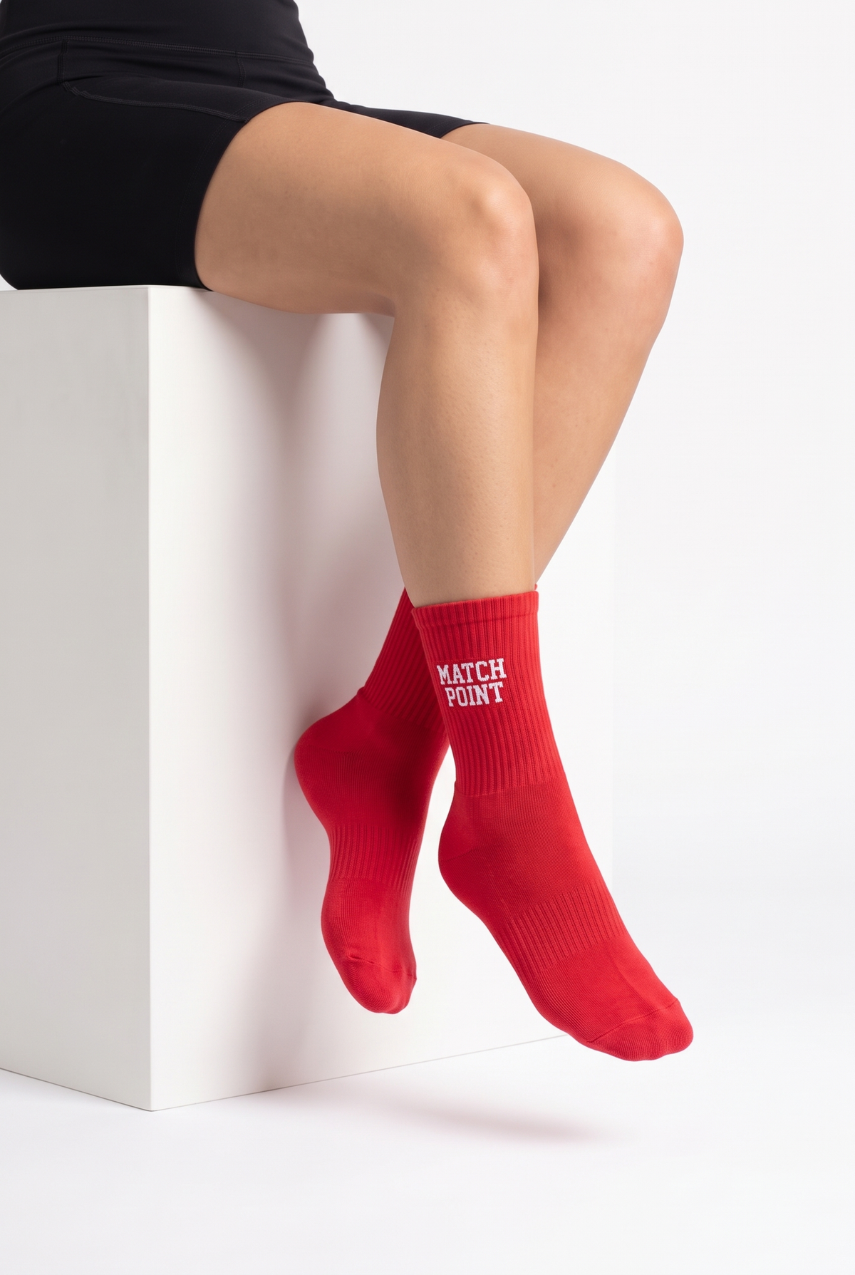 Model wearing red embroidered tennis socks, seated