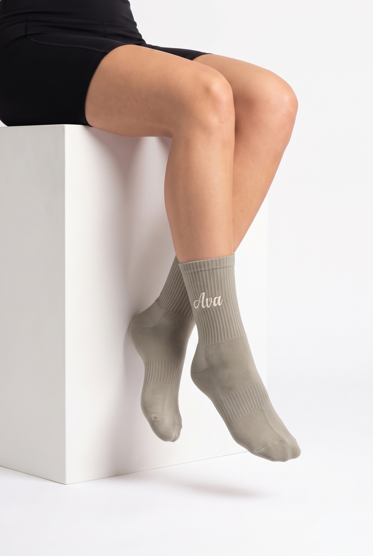 Model wearing khaki embroidered tennis socks, seated