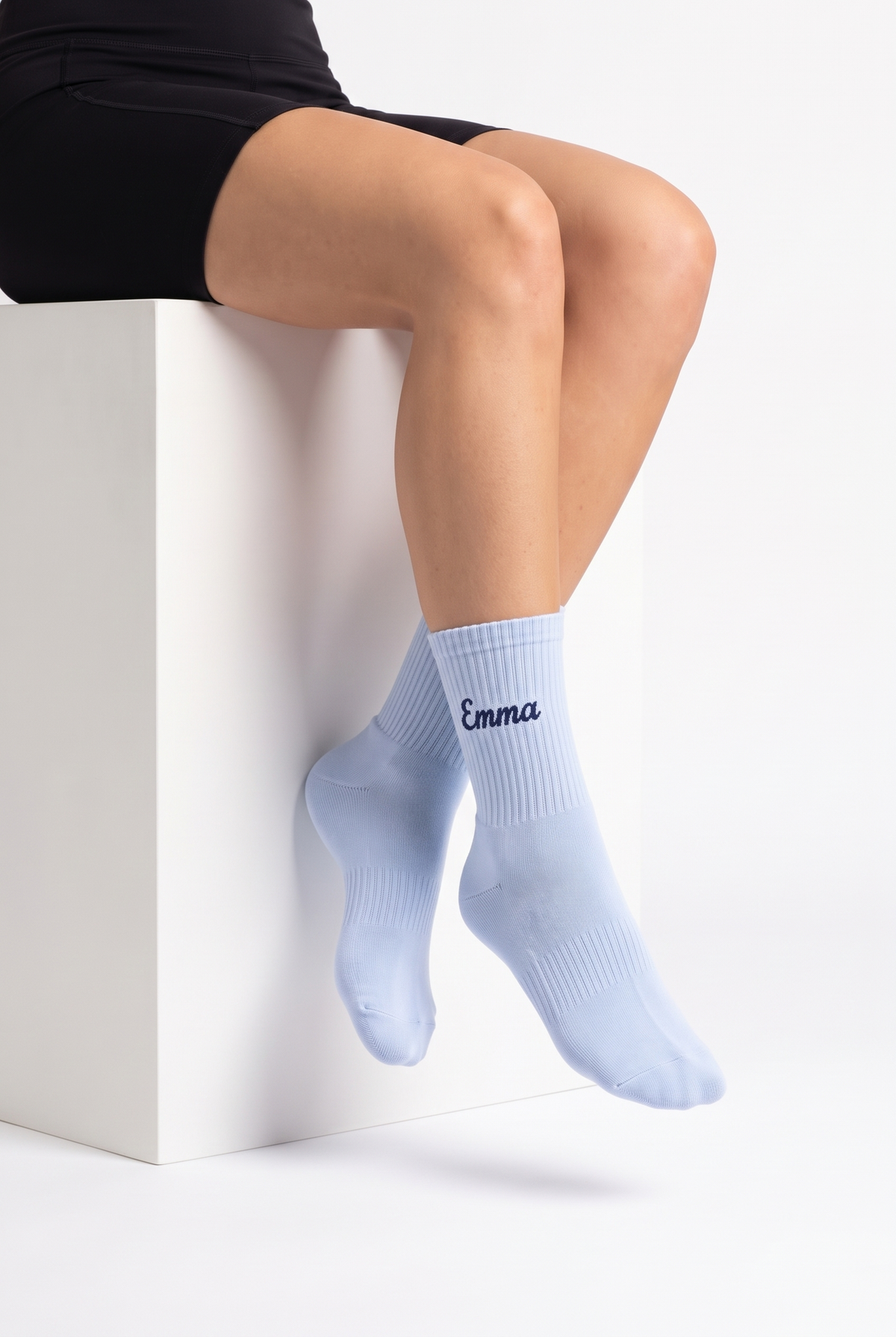 Model wearing baby blue embroidered tennis socks, seated