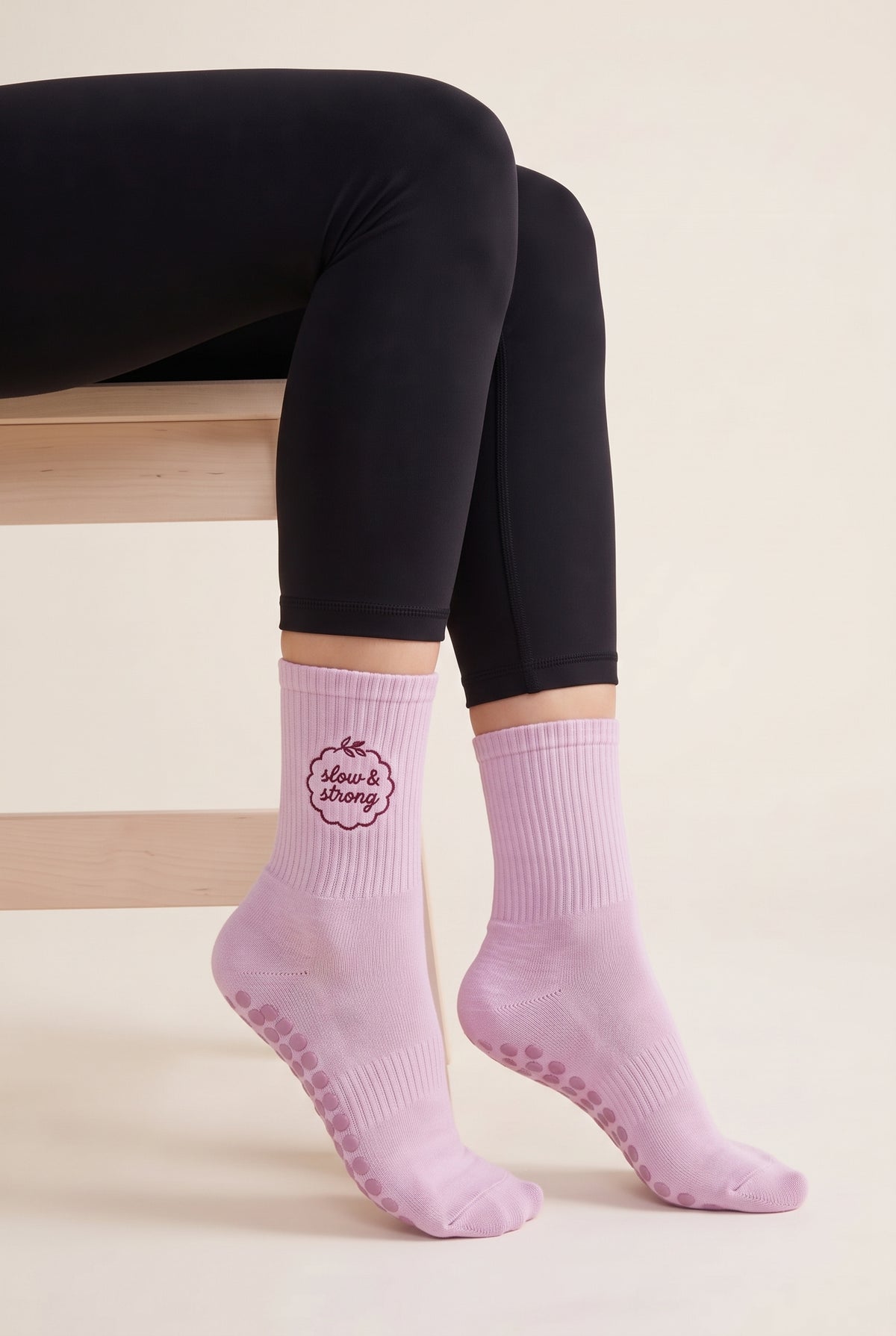 Model wearing pink embroidered dot grip pilates socks, seated