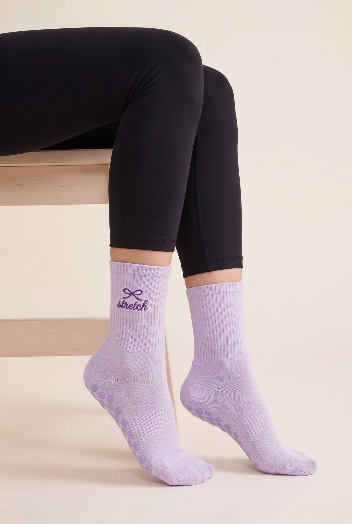 Model wearing lavender embroidered dot grip pilates socks, seated