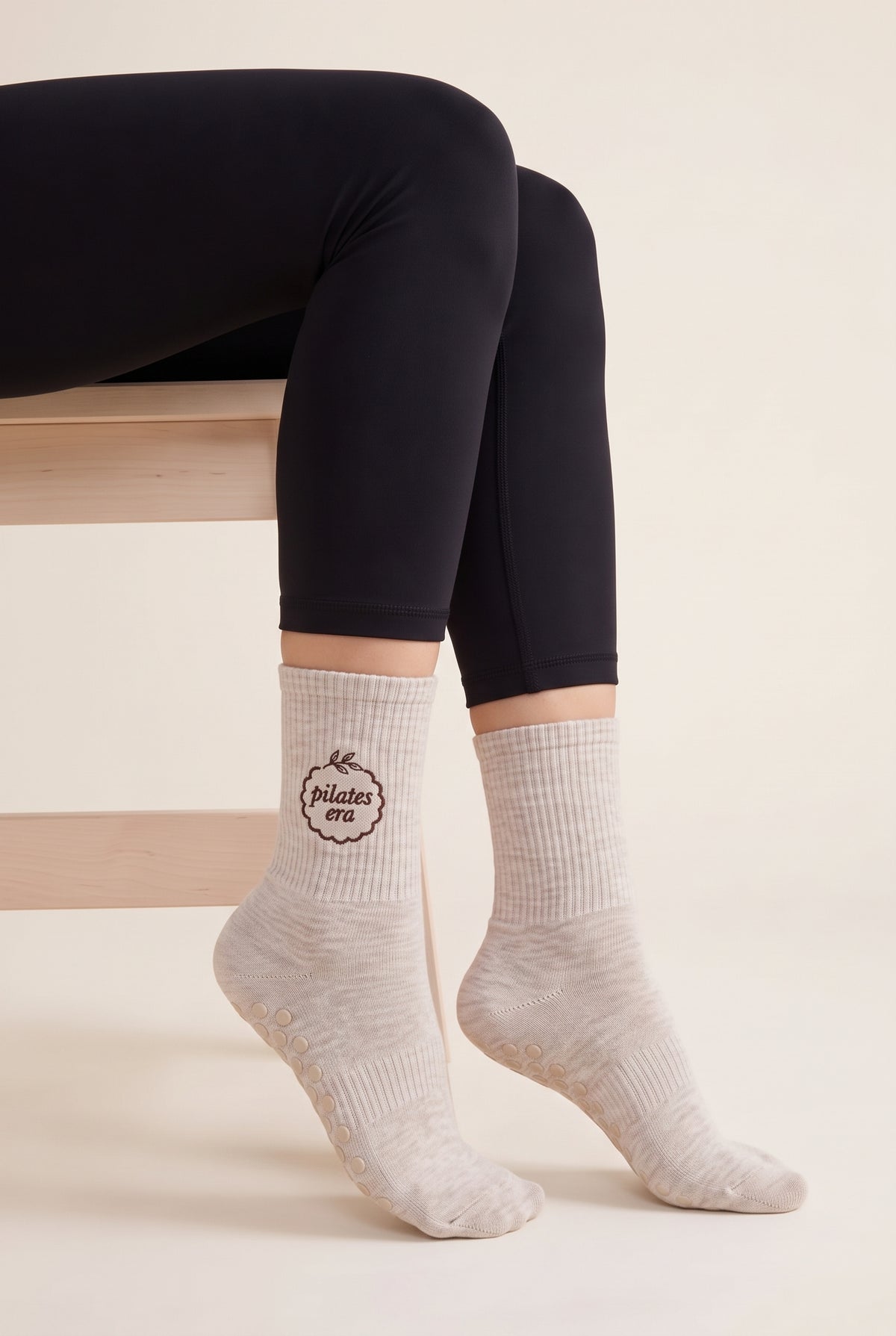 Model wearing beige melange embroidered dot grip pilates socks, seated