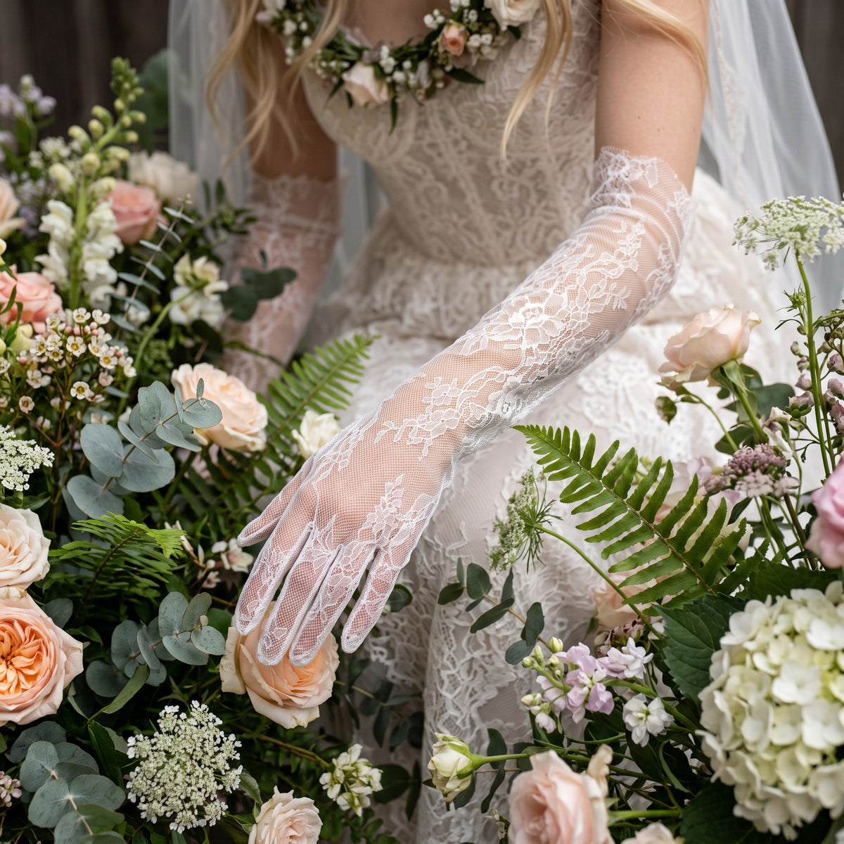Above-elbow white Chantilly lace gloves with scalloped edges, fingers covered.