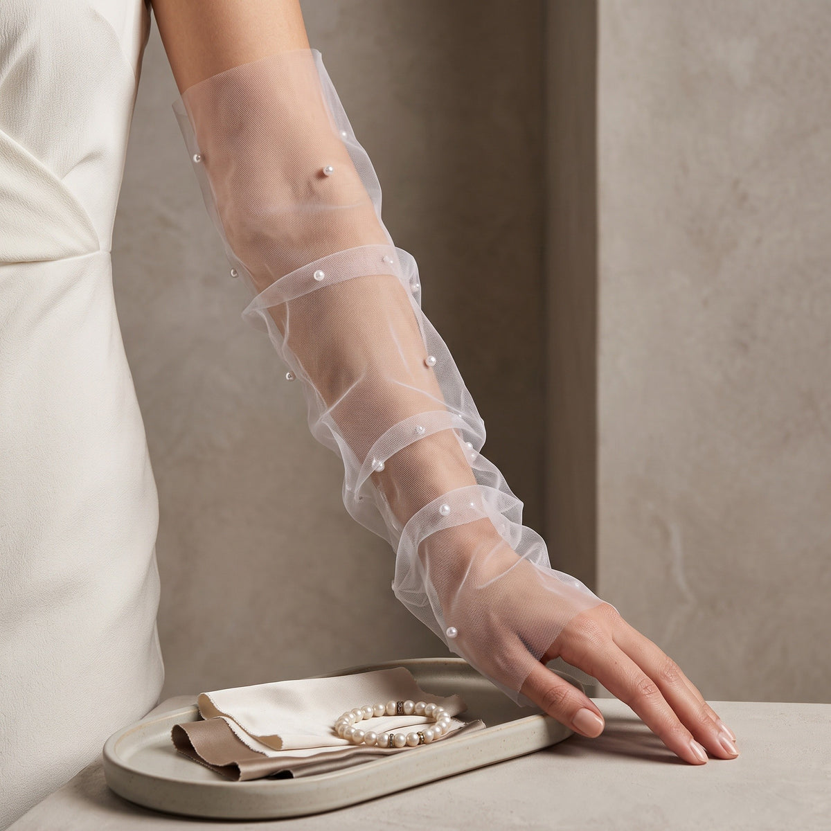 White tulle arm cuffs with scattered pearls and a ruffle edge, fingerless.