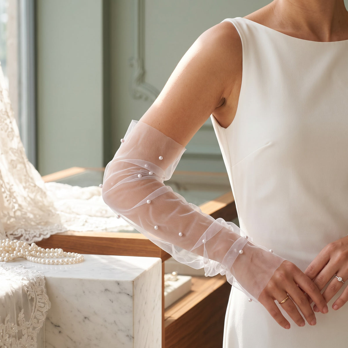 White tulle arm cuffs with scattered pearls and a ruffle edge, fingerless.