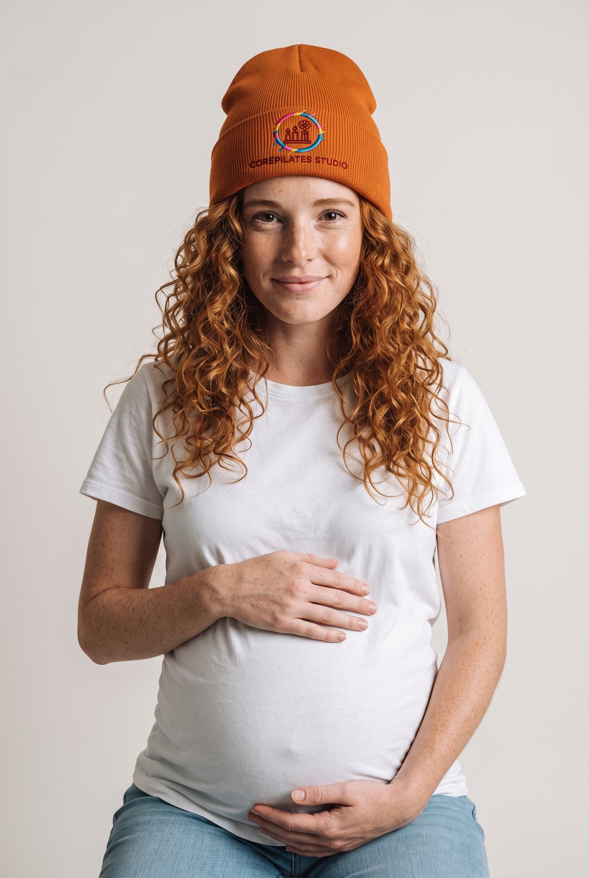 Model wearing a orange Eddia beanie with custom cuff embroidery