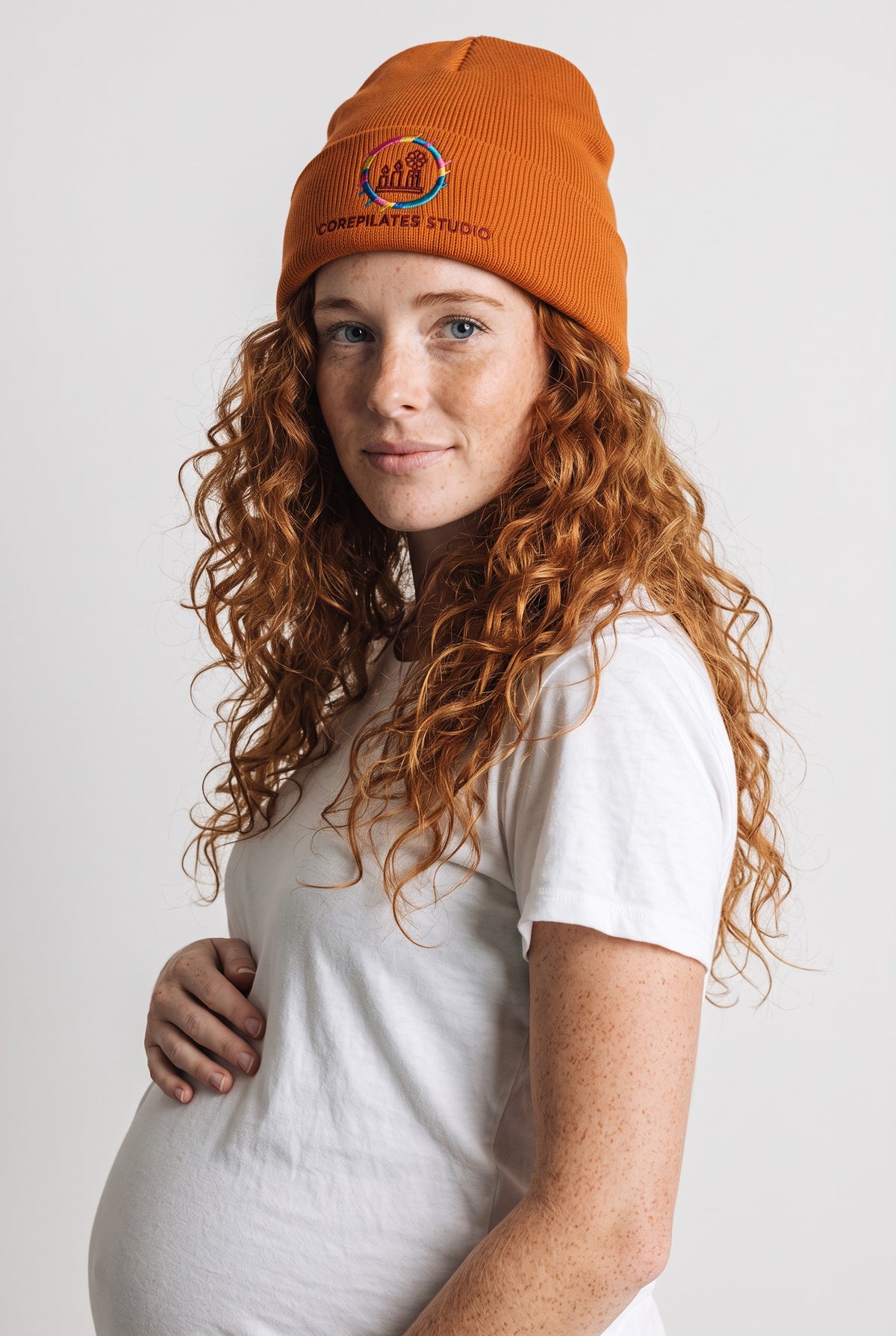 Model wearing a orange Eddia beanie with custom cuff embroidery