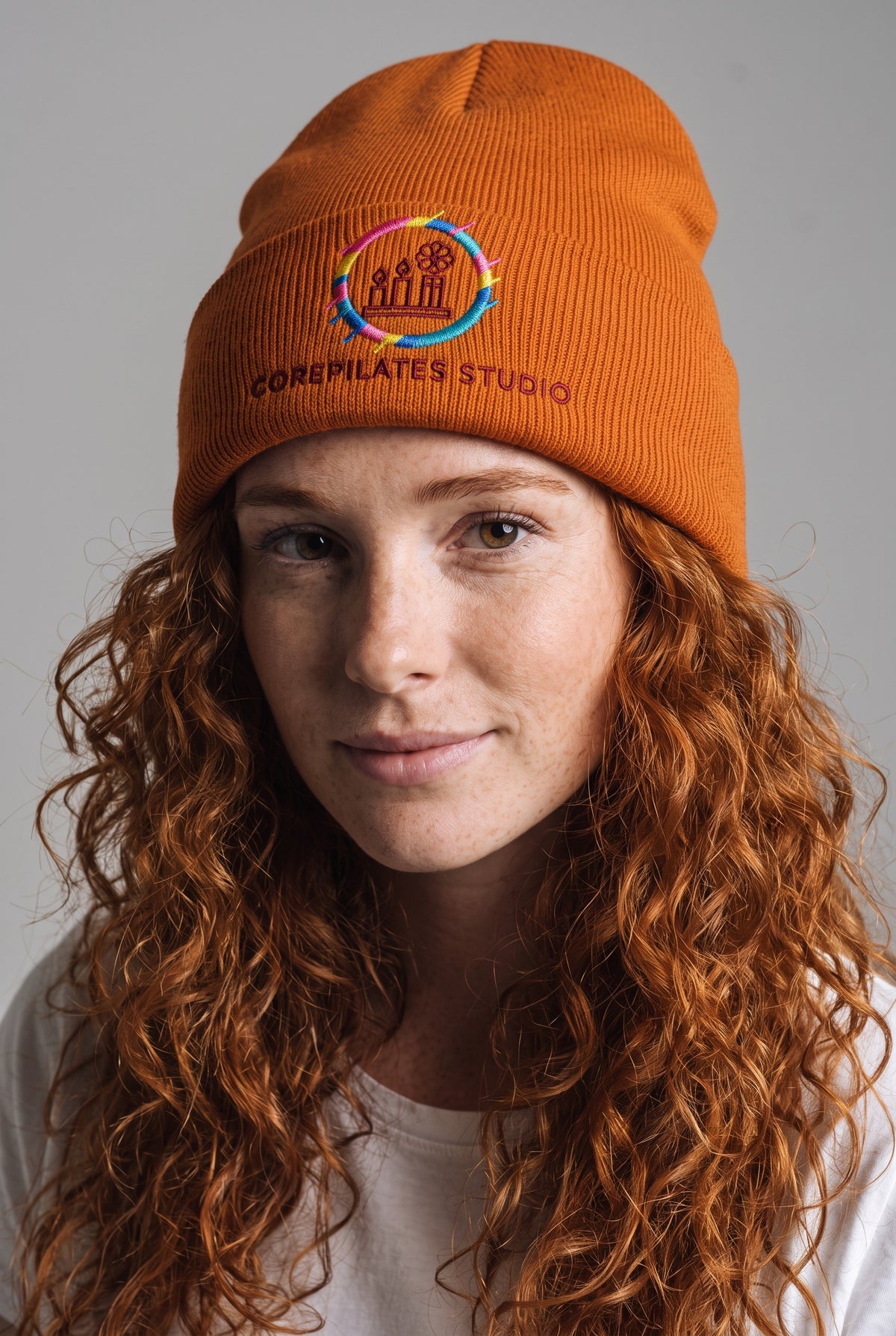 Model wearing a orange Eddia beanie with custom cuff embroidery