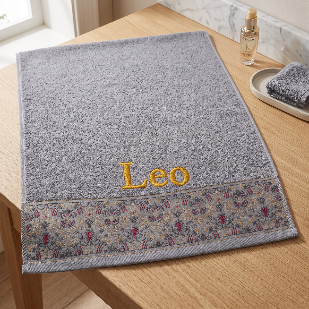 Leo personalized hair towel, gold serif embroidery on light gray cotton with a patterned border — photo 3