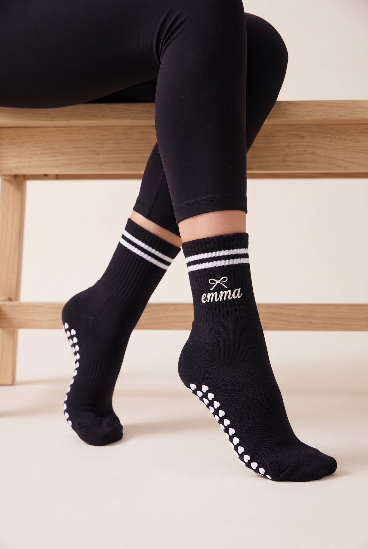 Model wearing black crew pilates grip socks beside a studio bench