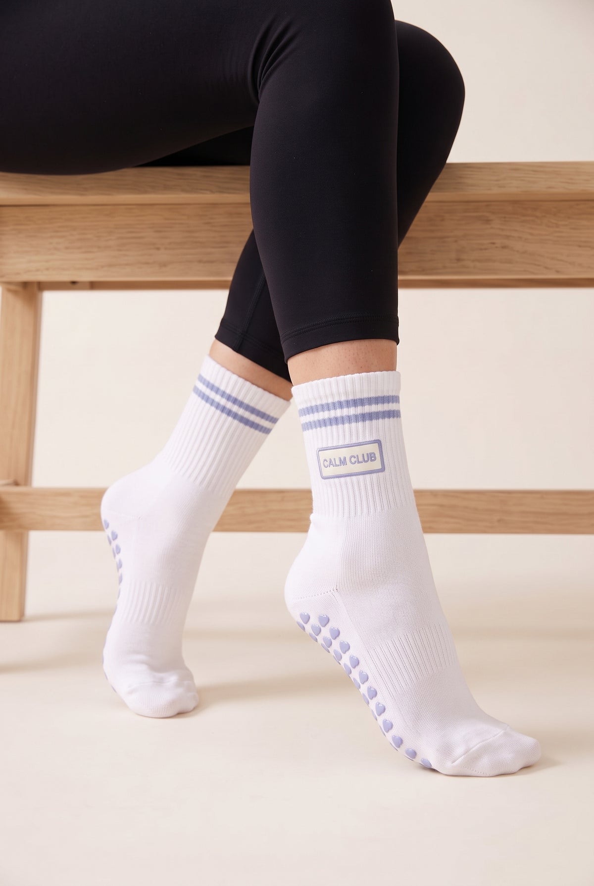 Model wearing ice blue crew pilates grip socks beside a studio bench