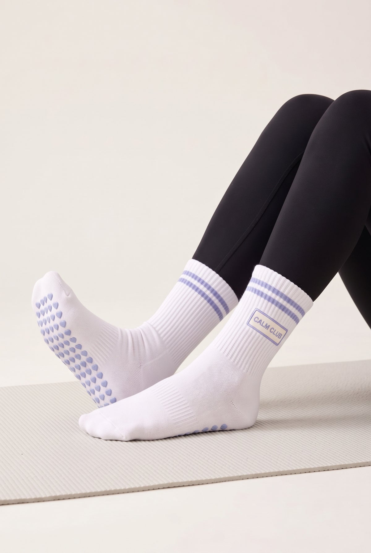 Model wearing ice blue crew pilates grip socks on a mat