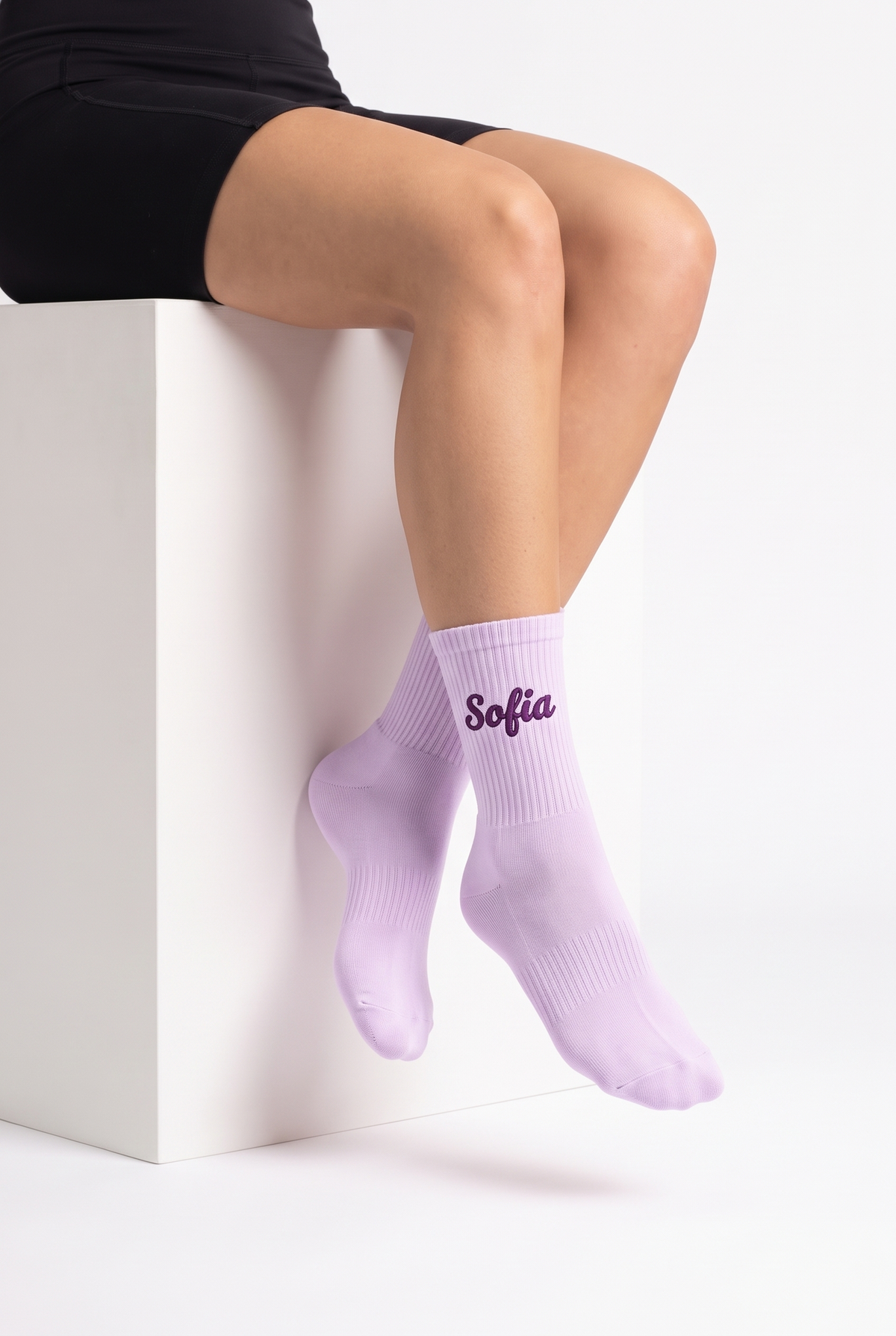 Model wearing lavender embroidered tennis socks, seated