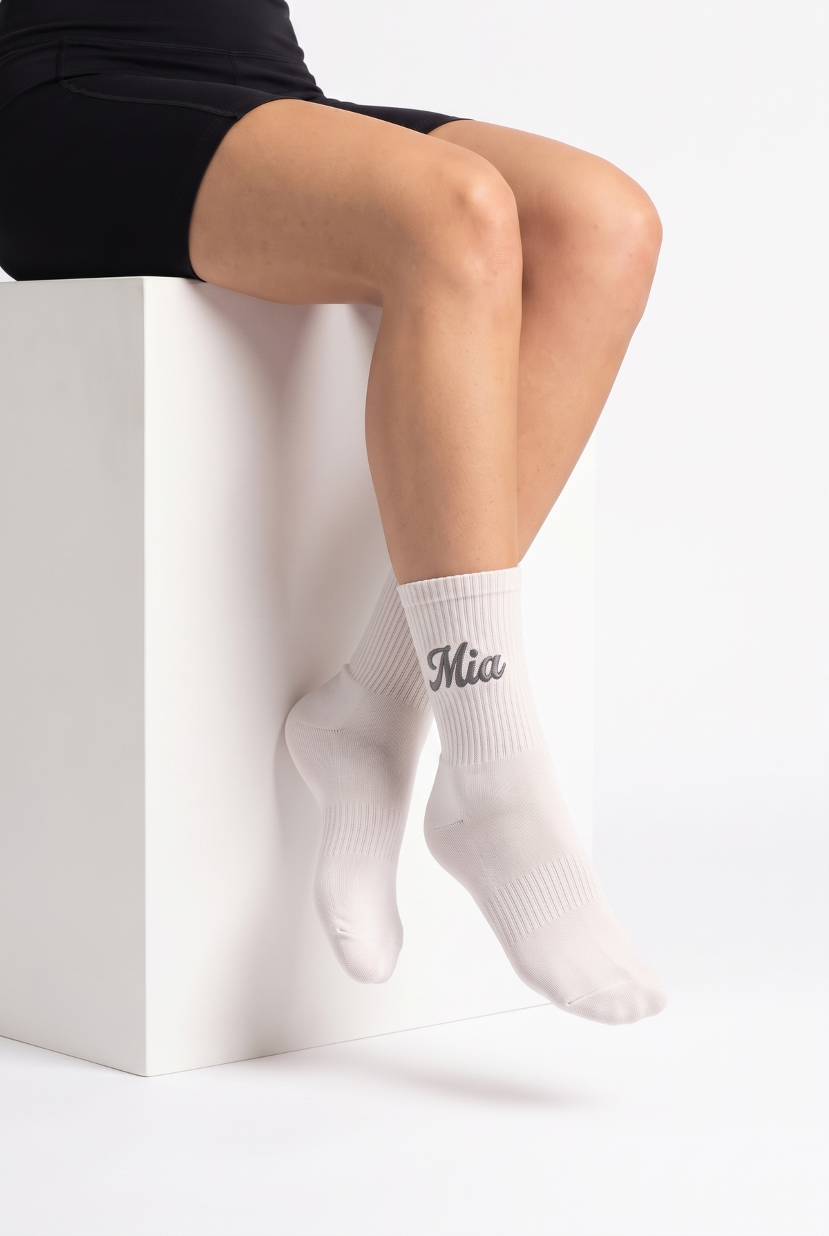 Model wearing off white embroidered tennis socks, seated