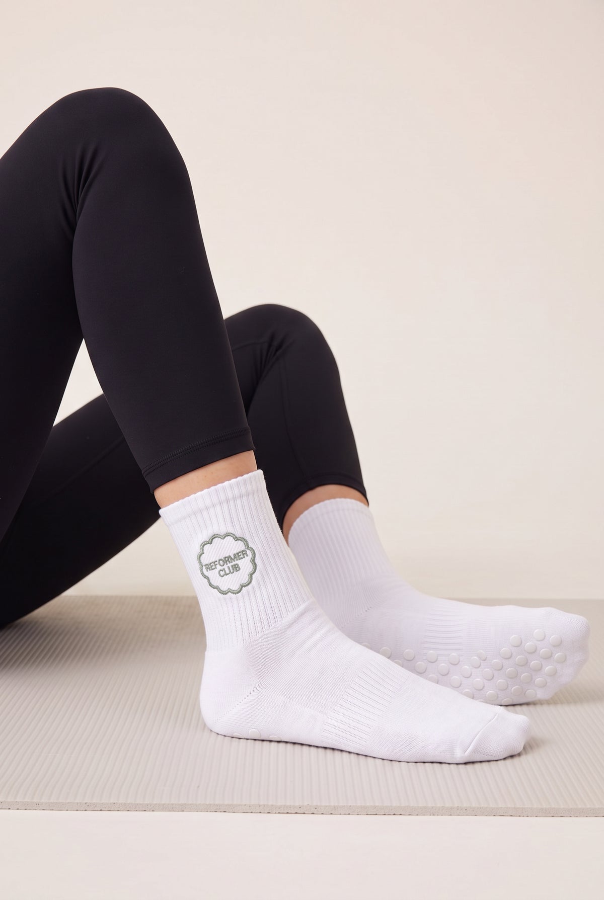 Model wearing white embroidered dot grip pilates socks