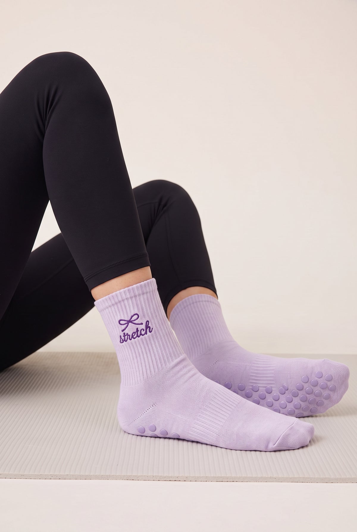 Model wearing lavender embroidered dot grip pilates socks