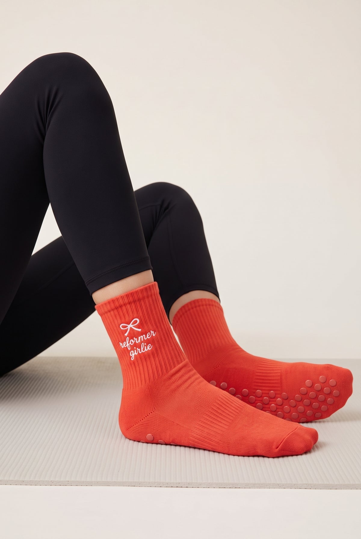 Model wearing orange embroidered dot grip pilates socks