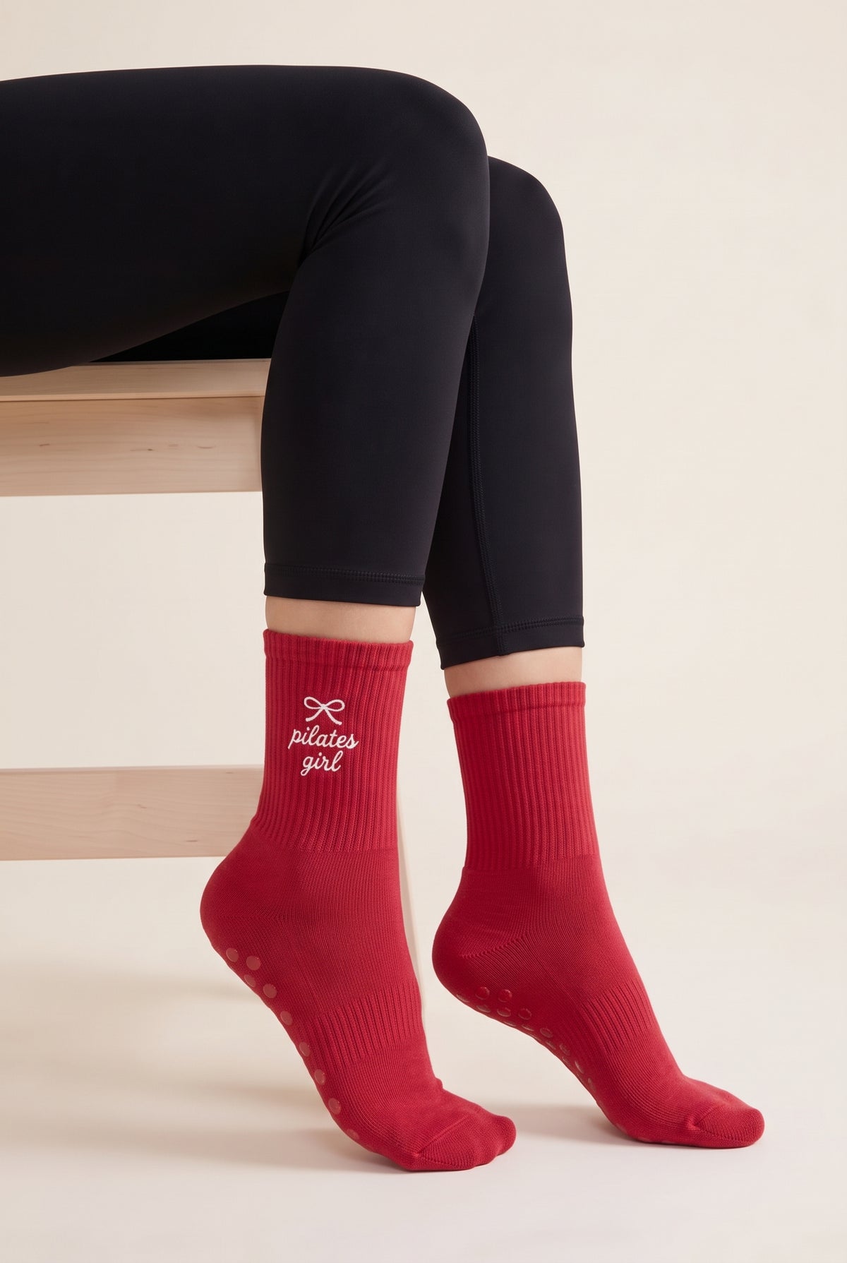 Model wearing red embroidered dot grip pilates socks, seated