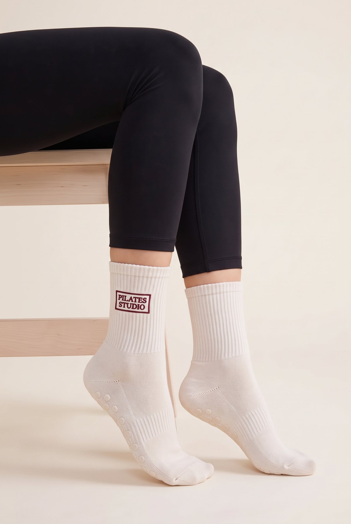 Model wearing off white embroidered dot grip pilates socks, seated