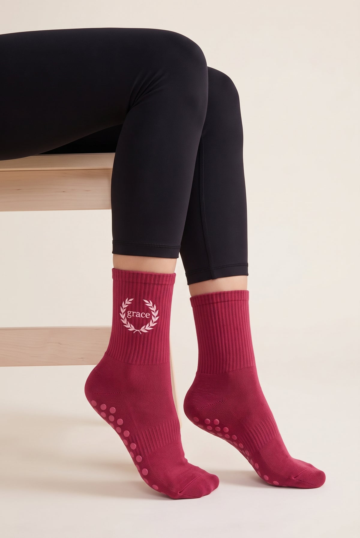 Model wearing berry embroidered dot grip pilates socks, seated