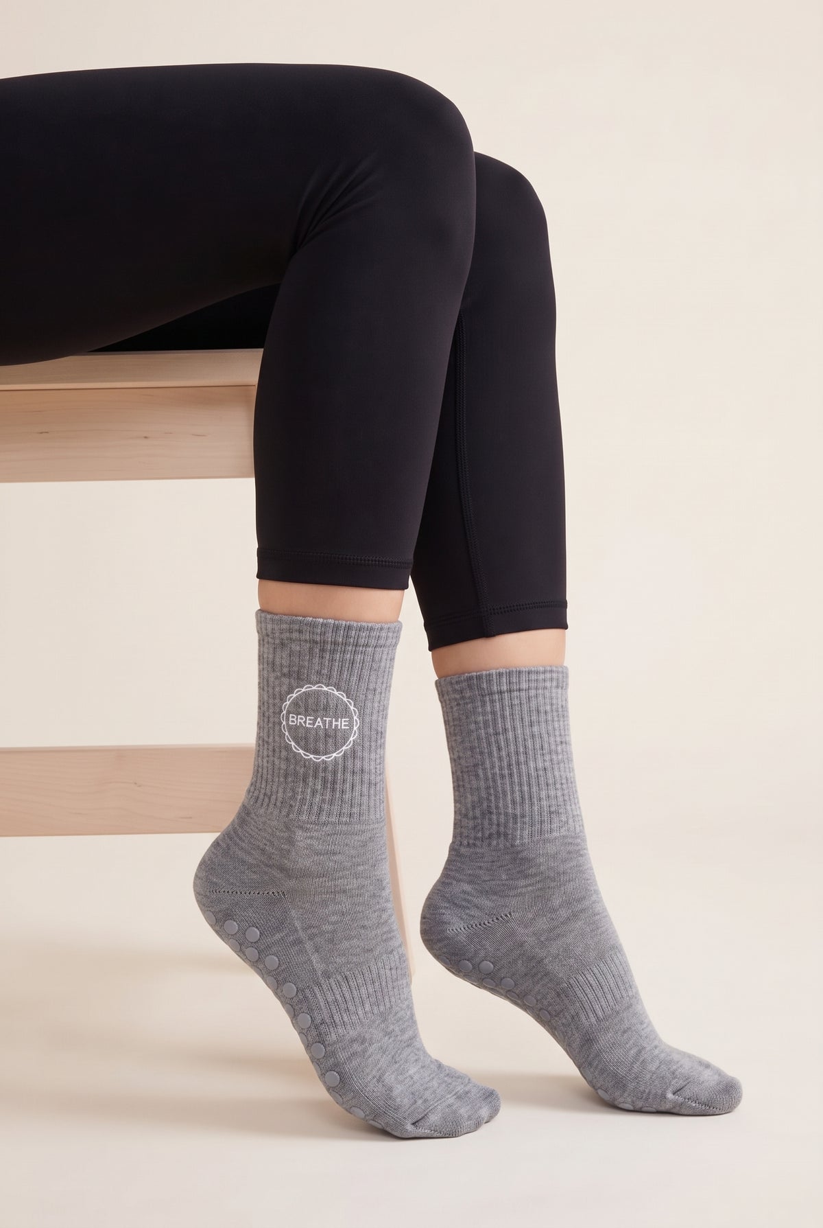 Model wearing grey embroidered dot grip pilates socks, seated