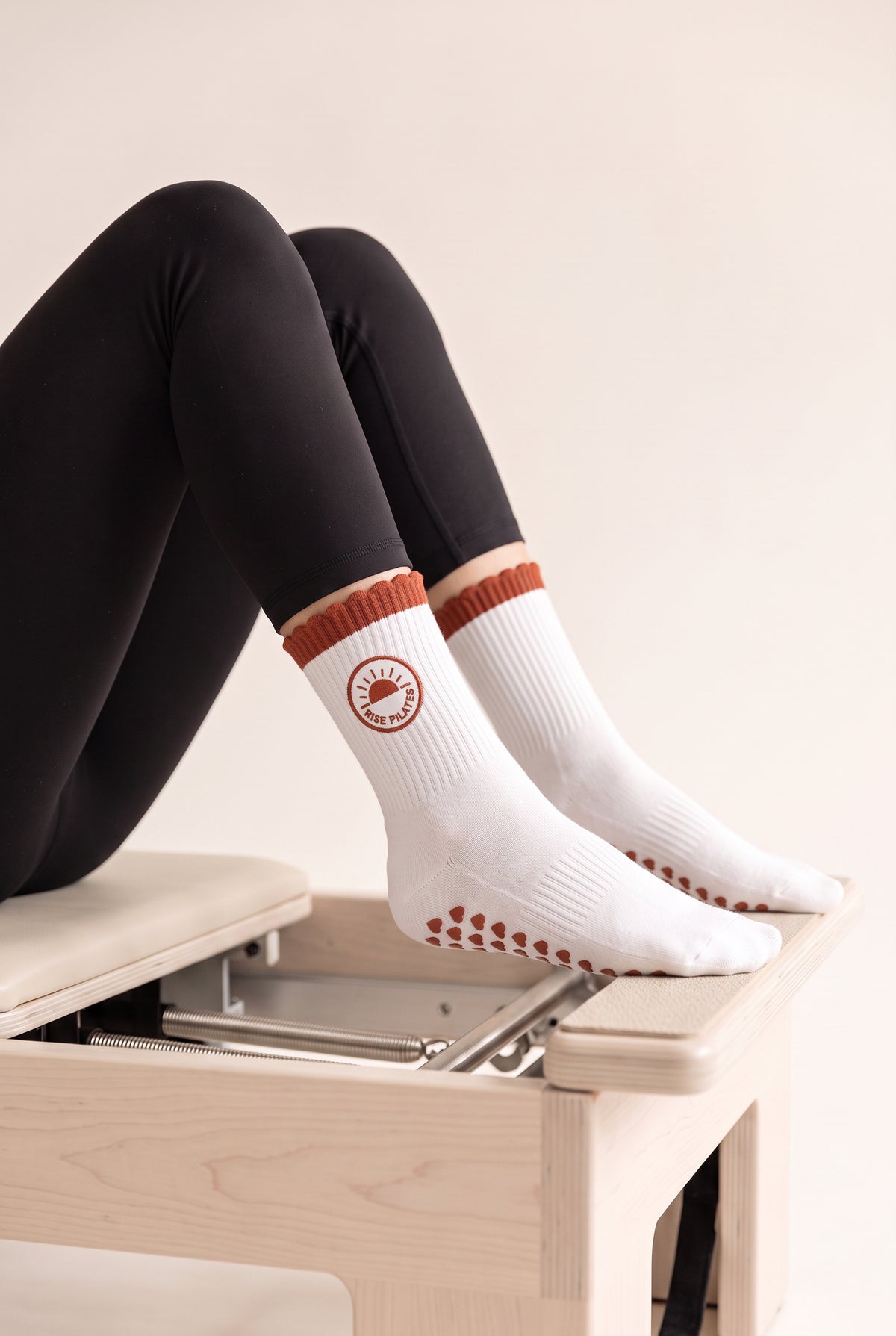 Orange ruffle pilates grip socks, worn on a reformer — embroidered to order
