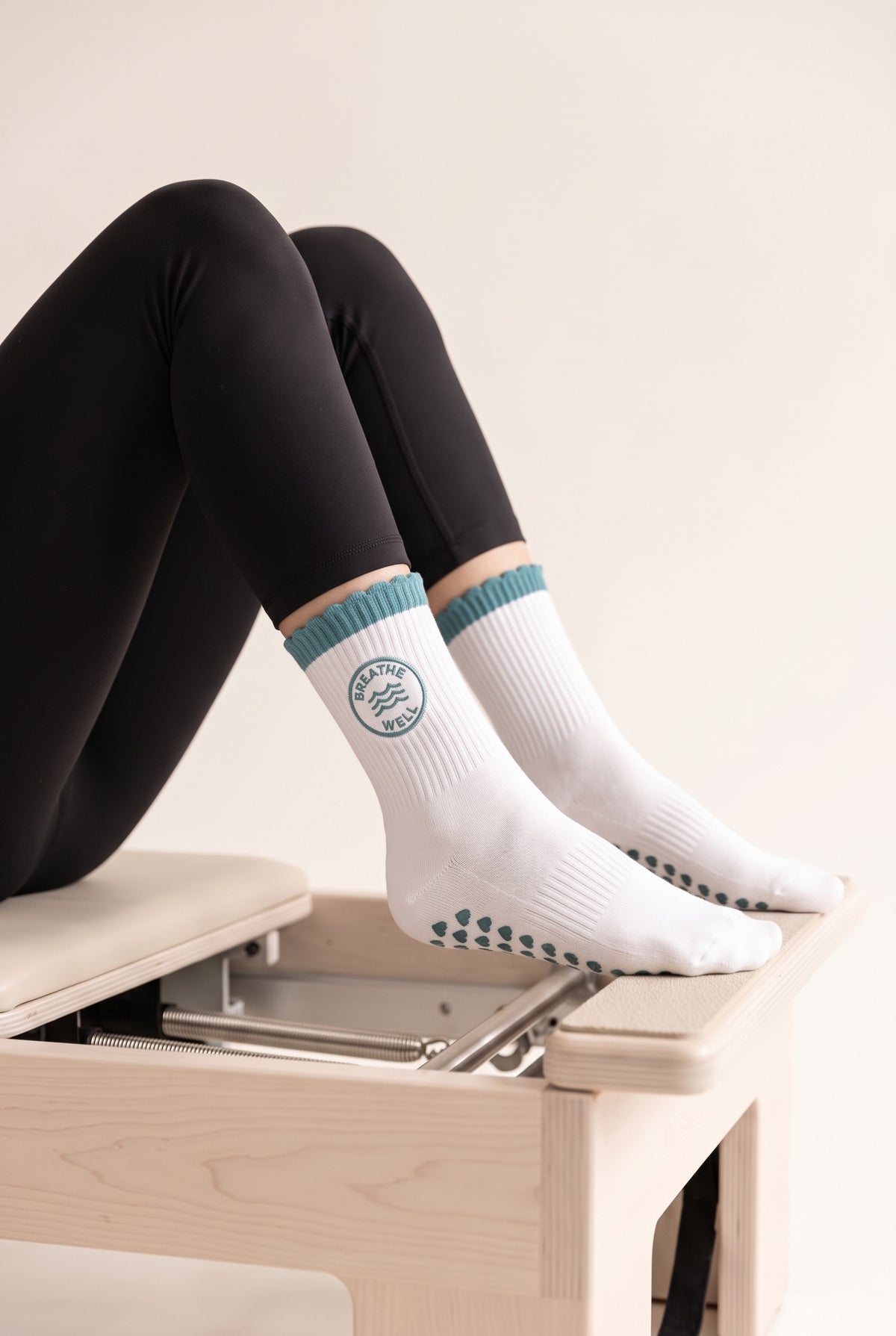 Turquoise ruffle pilates grip socks, worn on a reformer — embroidered to order